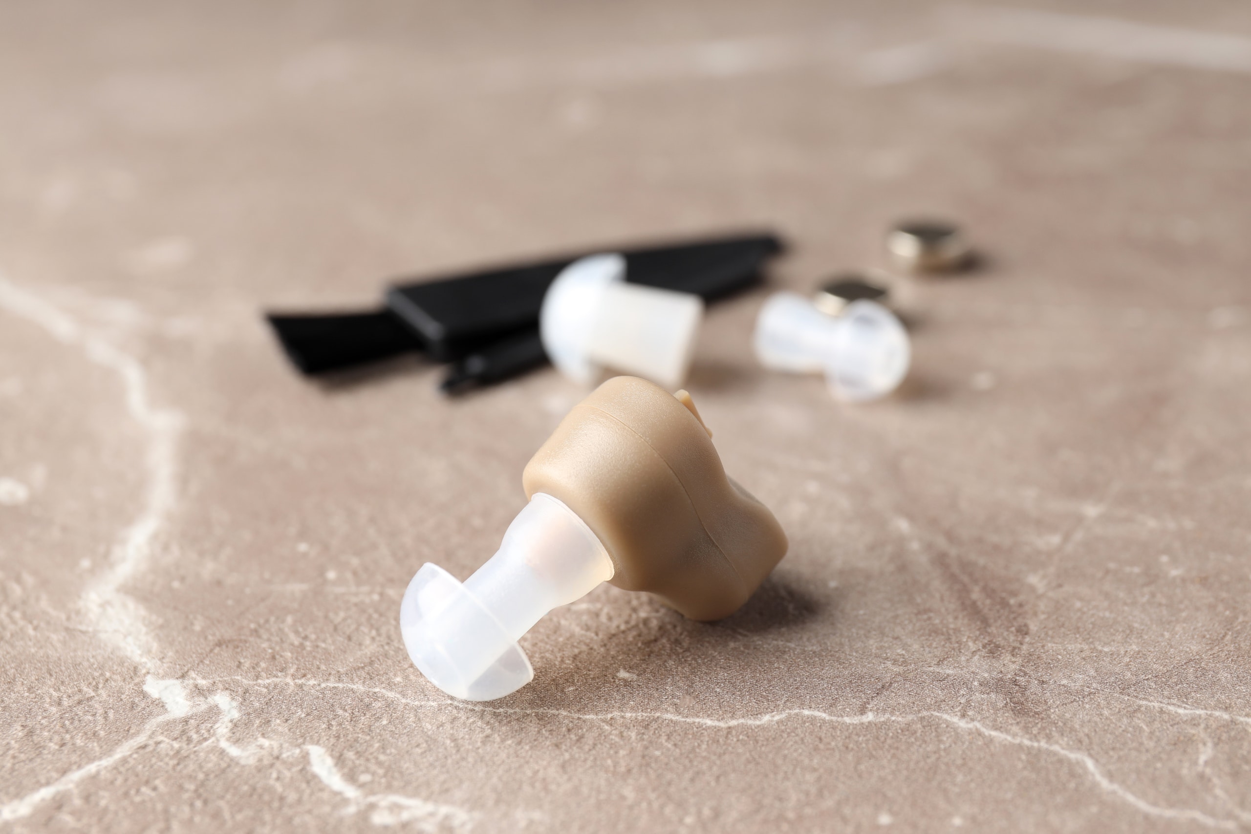 Concept of health care with hearing aid on beige textured backgr Concept of health care with hearing aid on beige textured background