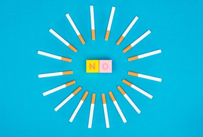 Flat lay with colorful letter cubes and cigarettes isolated on blue, stop smoking concept