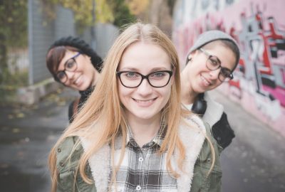 Three sisters on street, graffiti wall in background